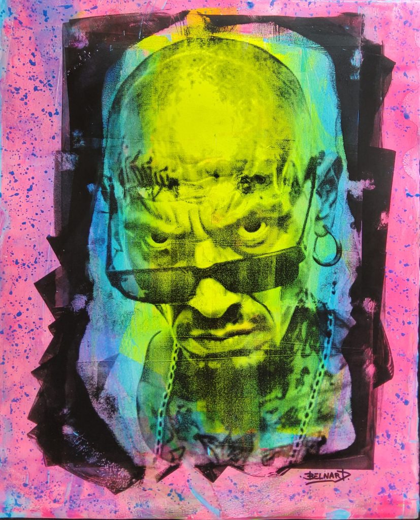 Portrait frontal d’homme chauve portant des lunettes noires, regard intense, sur fond rose et bleu électrique.